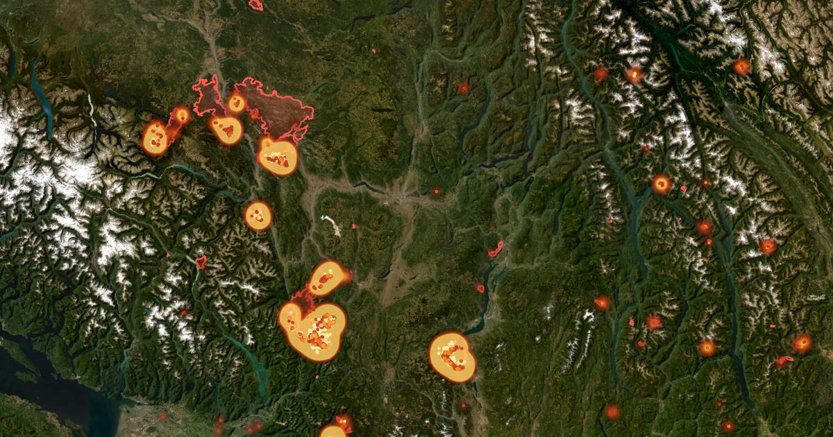 Satellite view of southern British Columbia with wildfire hotspots glowing orange and mapped fire perimeters outlined in red.